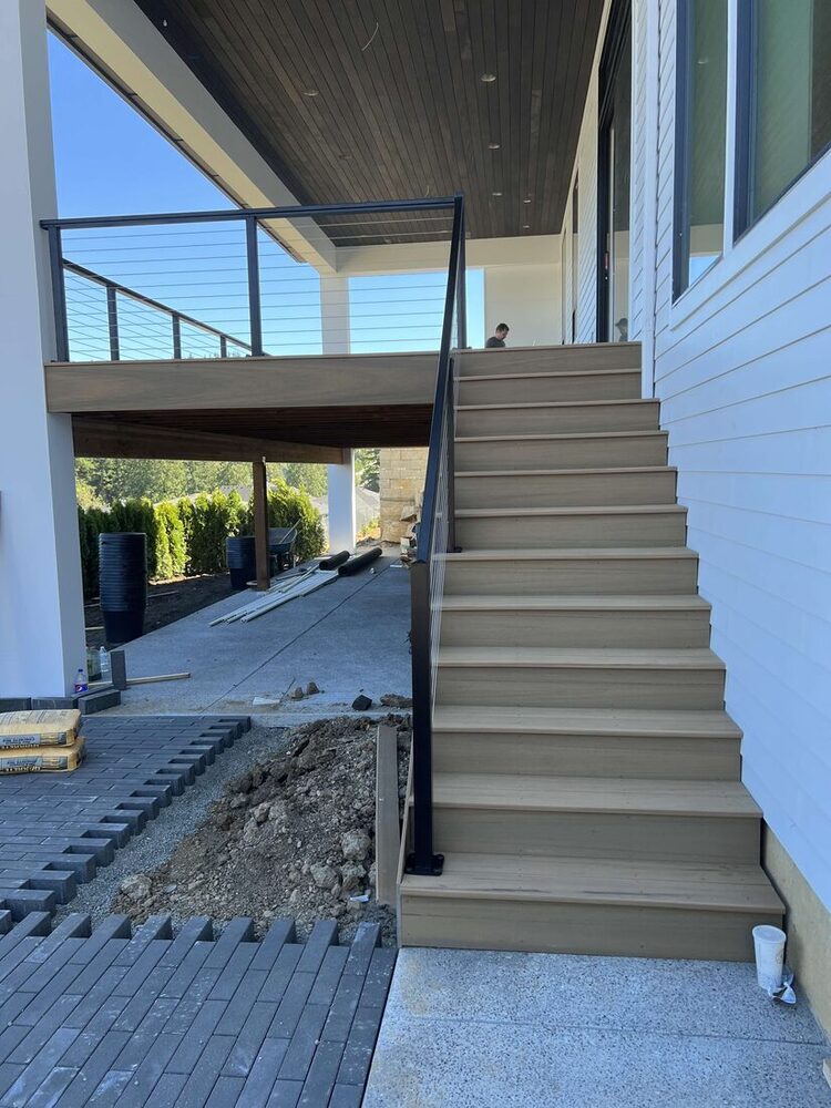 Custom composite deck stairs with cable railing and covered outdoor living space