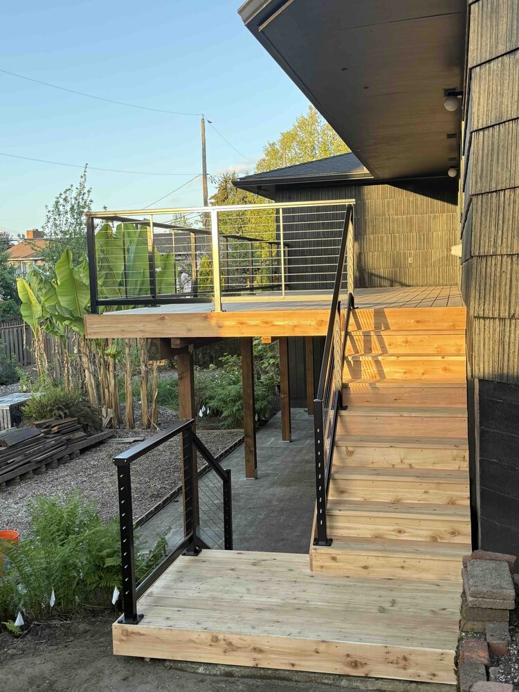 Custom wood deck stairs with intermediate landing and black cable railing