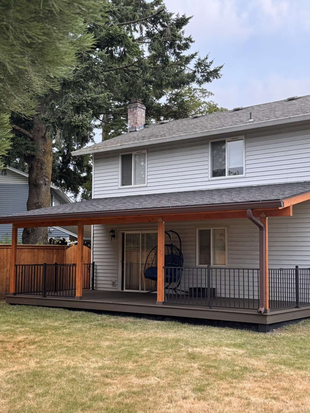 covered backyard deck with cedar posts and black railing